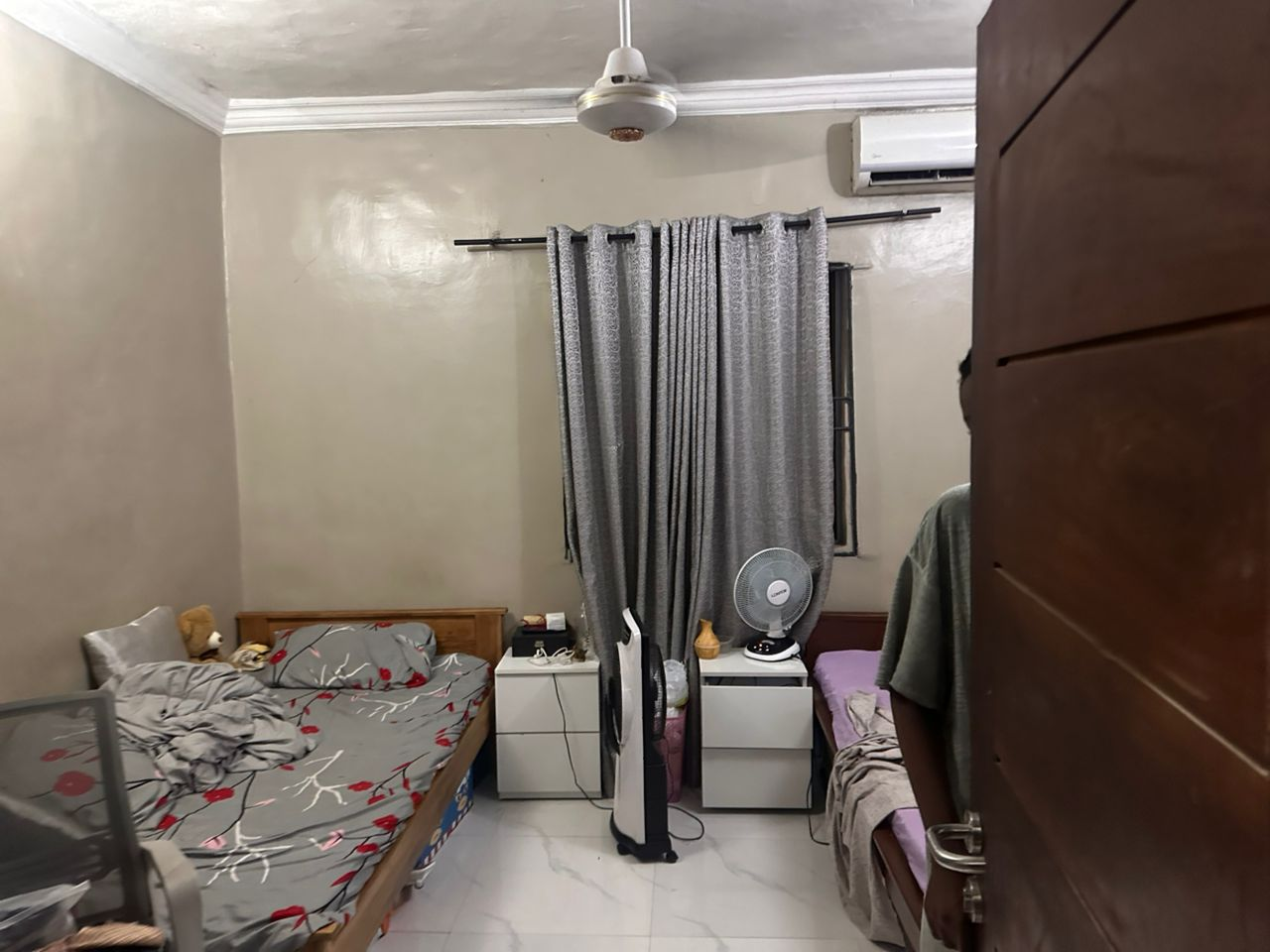Bed space room at Rilwan AJALA Homes with grey floral bedding, fan and air conditioning unit