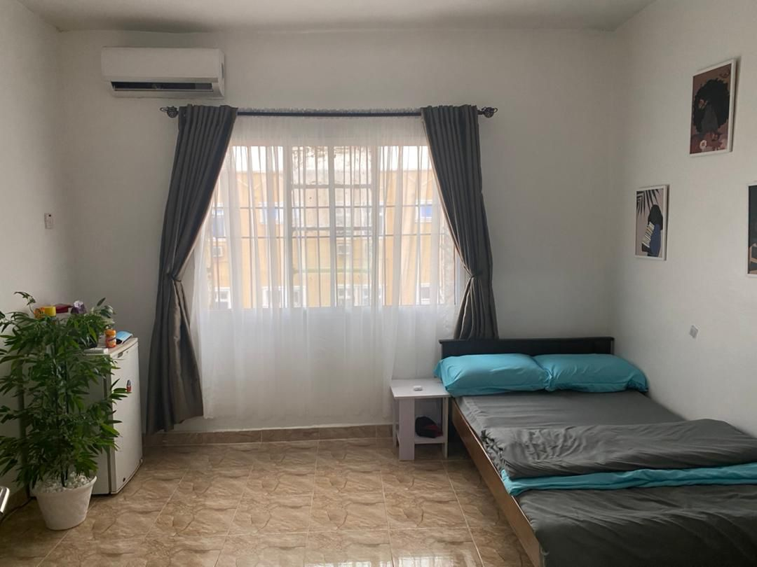 Spacious mini flat room at Rilwan AJALA Homes Enterprise Yaba Lagos with air conditioning, teal bedding, fridge and indoor plant