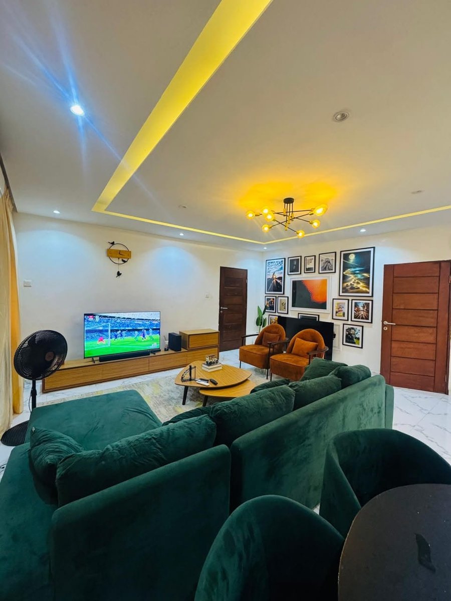 Mini flat living area at Rilwan AJALA Homes with green velvet sofa, gallery wall and smart TV