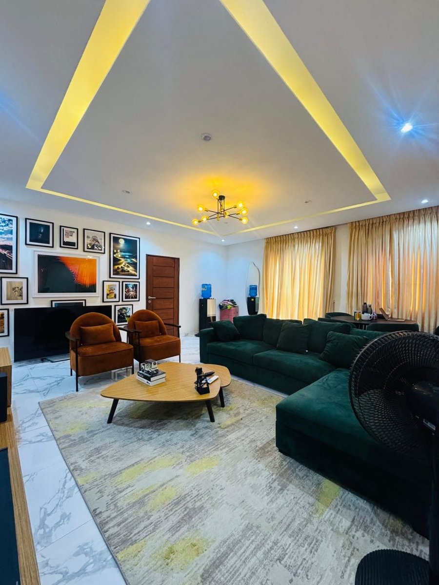 Mini flat living area at Rilwan AJALA Homes with velvet armchairs, gold curtains and statement chandelier