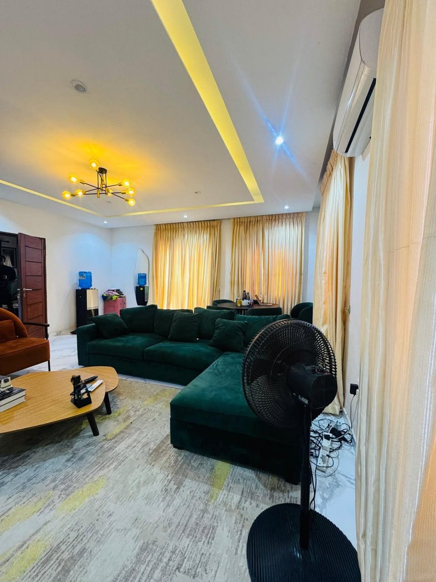 Mini flat living area seating at Rilwan AJALA Homes with air conditioning and gold curtains